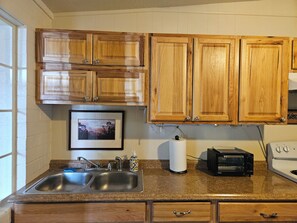Una cocina con armarios de madera, un lavamanos doble, un tostador y una estufa.