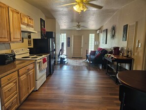 A kitchen with wooden cabinets, a stove, and a ceiling fan.