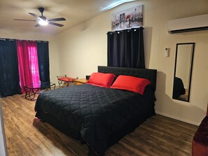 Un dormitorio con cama, ventilador de techo, mesa y una silla.