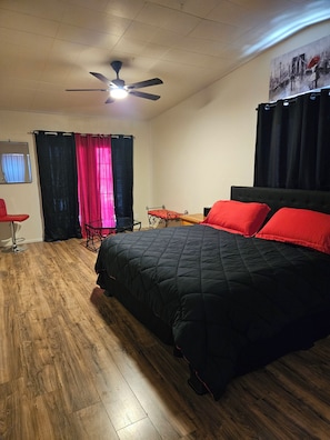 A bedroom with a bed, a ceiling fan, a chair, and a desk.