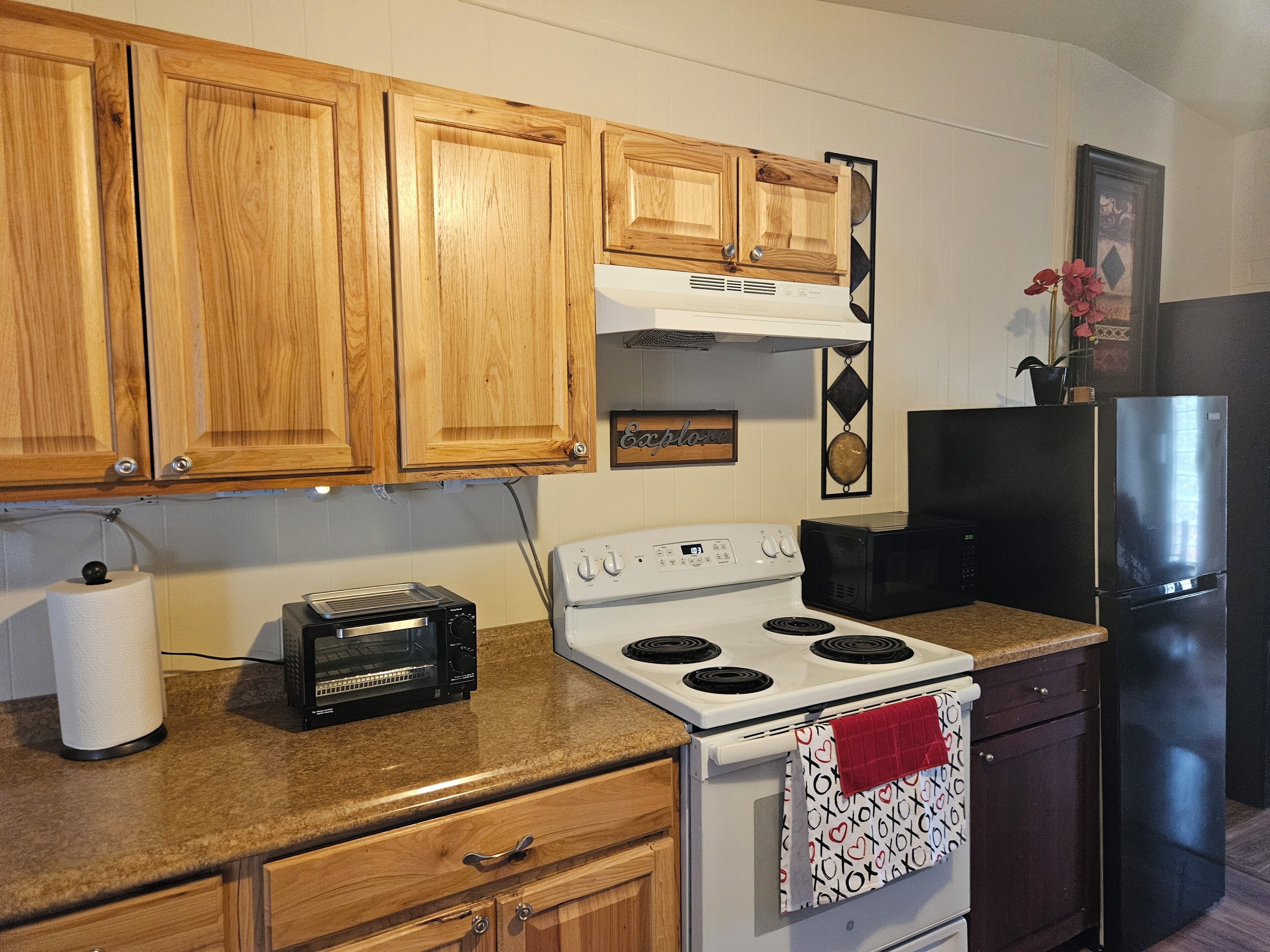 A kitchen with wooden cabinets, a white stove, a black microwave, and a black refrigerator.