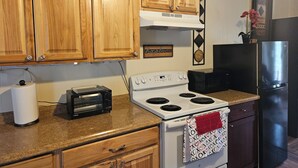 A kitchen with wooden cabinets, a white stove, a black microwave, and a black refrigerator. - Red Rock Rendezvous - Steps Away From Uptown Sedona Shops & Dining (Sedona)