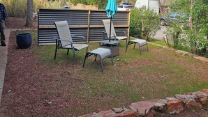 An outdoor seating area with a table and chairs, a green umbrella, and a brick border. - Red Rock Rendezvous - Steps Away From Uptown Sedona Shops & Dining (Sedona)