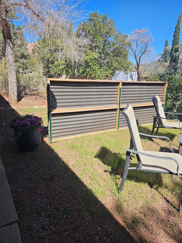 A patio area with a metal fence, two chairs, and a potted plant.