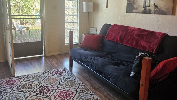 A room with a sofa, a patterned rug, a painting on the wall, and an air conditioning unit. - Red Rock Rendezvous - Steps Away From Uptown Sedona Shops & Dining (Sedona)