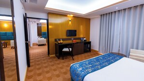 Una habitación de hotel con cama, escritorio, televisión y minibar.
