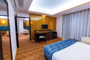 Et hotelværelse med seng, skrivebord, fjernsyn og minibar.