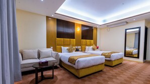 Habitación de hotel con dos camas, un sofá, una mesita y un espejo.