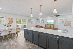 A modern kitchen with a large island, grey cabinets, and pendant lighting. - Sunnyside Villa - Beach Access, Fire Pit & Family Fun Near 30A, Sleeps 8 (Panama City Beach)