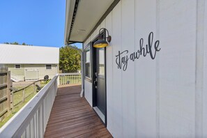 The property entrance displays a welcoming 'stay awhile' message on the exterior siding, inviting you to unwind and relax from the moment you arrive. - Sunnyside Villa - Beach Access, Fire Pit & Family Fun Near 30A, Sleeps 8 (Panama City Beach)