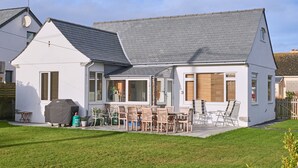 Une maison à deux étages dotée d’un patio, de meubles d’extérieur et d’un barbecue.