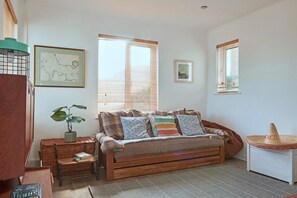 Ein gemütliches Zimmer mit einer Holzbank, einem kleinen Tisch mit einer Pflanze und einem gewebten Korb.