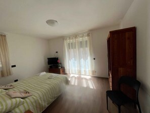 Ein Schlafzimmer mit Bett, Sessel, Fernseher und Holztür.