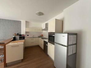A compact kitchen with a microwave, oven, and refrigerator. - Holiday apartment - a home-from-home in the Ledro Valley – Modern & Cosy (Tiarno Di Sopra)
