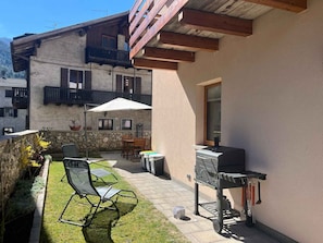 A patio with outdoor furniture, a barbecue grill, and a stone wall. - Holiday apartment - a home-from-home in the Ledro Valley – Modern & Cosy (Tiarno Di Sopra)