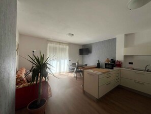 Eine kompakte Küche mit Essbereich, einem an der Wand montierten Flachbildfernseher und einem Blumentopf.