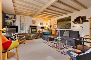 Ein gemütliches Wohnzimmer mit Kamin, einer Couch, einem Couchtisch und einem farbenfrohen Teppich.