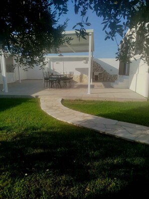 Ein Patio mit einem gepflasterten Weg, der zu einer Sitzgruppe mit Stühlen und einem Tisch führt.
