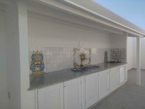 A modern kitchen with white cabinets, a granite countertop, and decorative tiles. - Villa with garden and air conditioning (Santa Maria del Focallo)