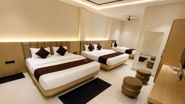 A hotel room with two beds, a mirror, a wooden wardrobe, and a small round ottoman. - Hotel Mewada (Ujjain)