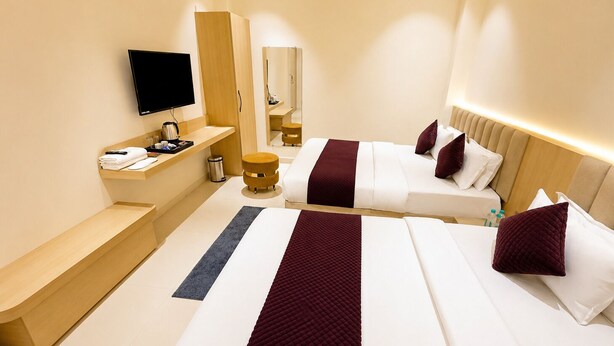 Habitación de hotel con dos camas, una televisión de pantalla plana, un minibar y un espejo.