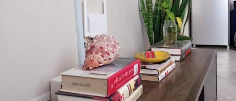 Une pièce avec une table en bois, des livres, un téléviseur, un réfrigérateur et une plante en pot.