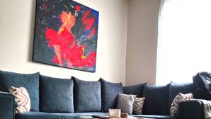 Een woonkamer met een donkerblauwe bank, een ronde salontafel en een tapijtend met een patroon.