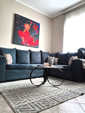 A living room with a dark blue sofa, a round coffee table, and a patterned rug. - Serene Palace (Nairobi)