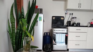 Een keuken met een koelkast, een koffiezetapparaat, een wastafel en kastjes.