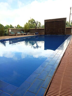 A swimming pool with a tiled edge, a wooden deck, and a metal railing. - Serene Palace (Nairobi)