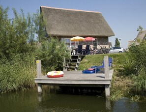 A wooden dock extending over water with a building in the background. - Detached Spacious Beach Villa for 8 (Makkum)