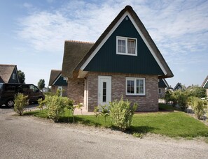 A residential house with a brick facade, a white door, and a thatched roof. - Detached Spacious Beach Villa for 8 (Makkum)
