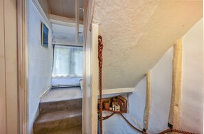 Eine enge Treppe führt zu einer Zwischenebene mit einem Fenster und einer kleinen Ablagefläche.