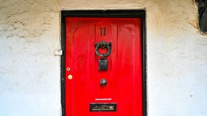 Una porta rossa con una spilla, una serratura e una fessura per la posta.
