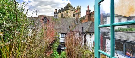 A narrow stone pathway leading to a traditional building with a steep roof and multiple chimneys.
