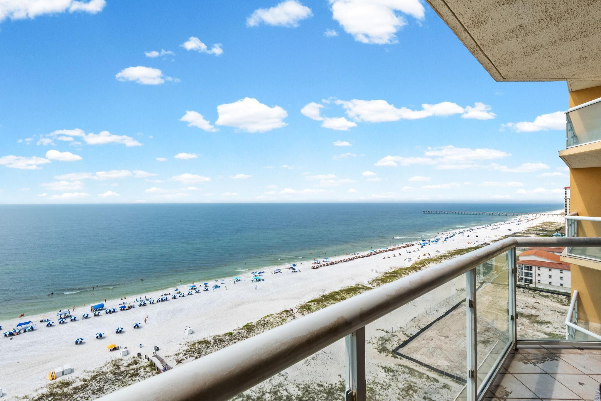 Een balkon met uitzicht op strand en zee.