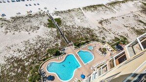 Um resort com área de piscina, acesso à praia e uma ponte que liga ao areal.