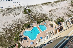 A resort with a pool area, beach access, and a bridge connecting to the beach. - Emerald Isle Unit 1402 (Pensacola Beach)