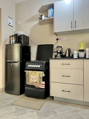 Eine kleine Küche mit Kühlschrank, Backofen, Mikrowelle und einer Kaffeemaschine.
