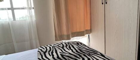 A bedroom with a zebra-patterned bedspread, a white towel, and a toothbrush on the bed.