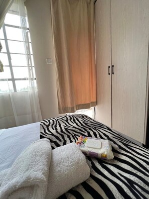 Ein Schlafzimmer mit einem Bettzeug mit ZEBRA-Muster, einem weißen Handtuch und einer Zahnbürste auf dem Bett.