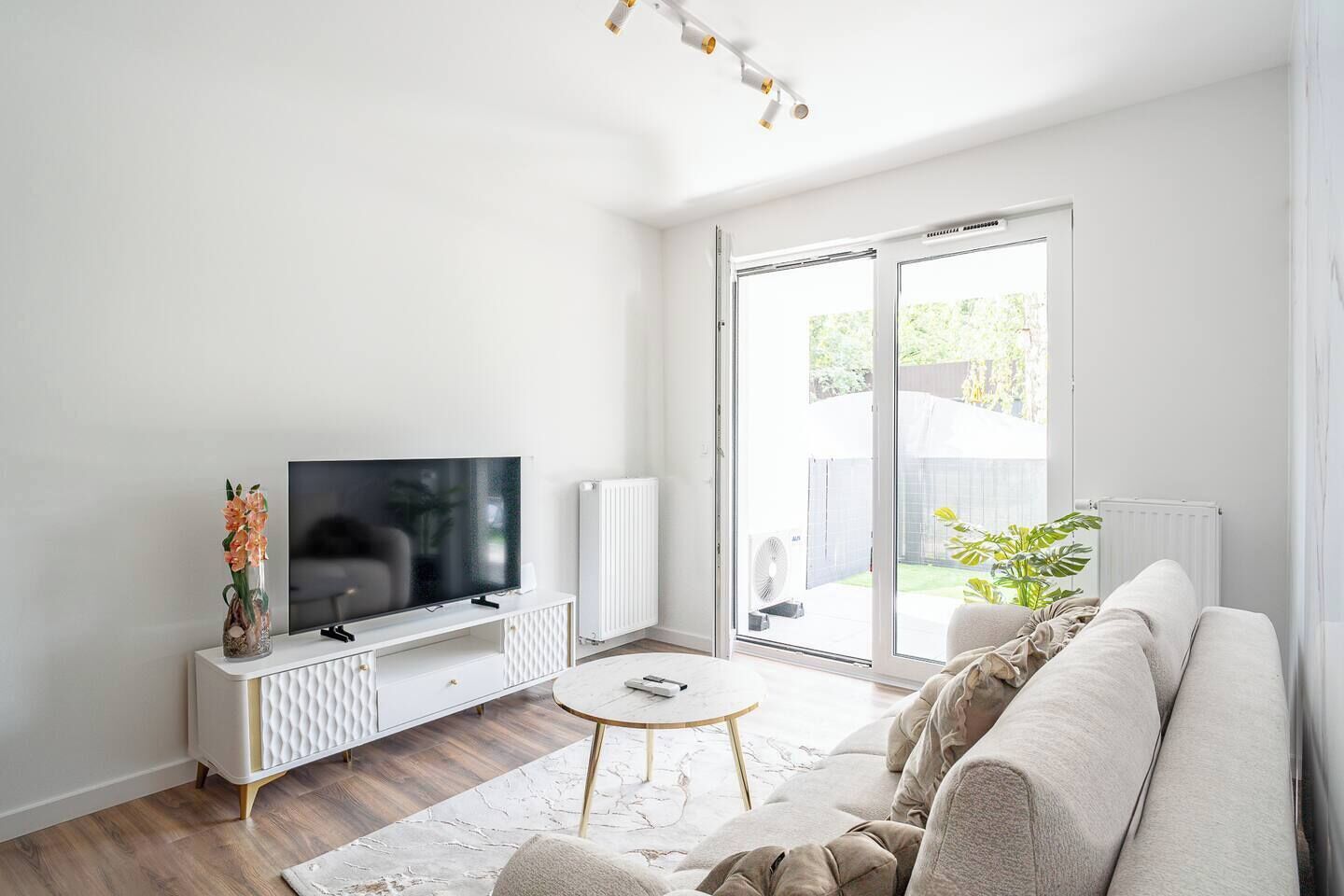 A modern living room with a flat-screen TV, a white cabinet, a round coffee table, and a sofa.