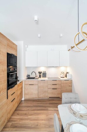 Eine moderne Küche mit Holzausstattung, einem eingebauten Backofen und einem Essbereich mit Tisch für Zwei.