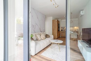 A modern living room with a sofa, a coffee table, and a TV. - Kraków City Apartment — Terrace & Parking (Kraków)