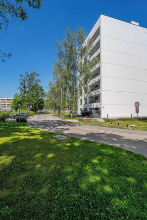 A modern building with a flat facade, a parking area, and a grassy foreground. - Kraków City Apartment — Terrace & Parking (Kraków)