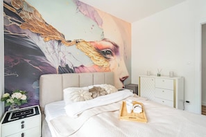 A bedroom with a large bed, a nightstand, a dresser, and a wall mural. - Kraków City Apartment — Terrace & Parking (Kraków)