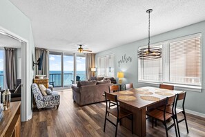A spacious living area with a balcony, a dining table with chairs, and a sofa. - Summerwind West 804 (Navarre)