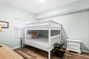 A bunk bed with a desk and chair, a nightstand, and a window with blinds. - Summerwind West 804 (Navarre)