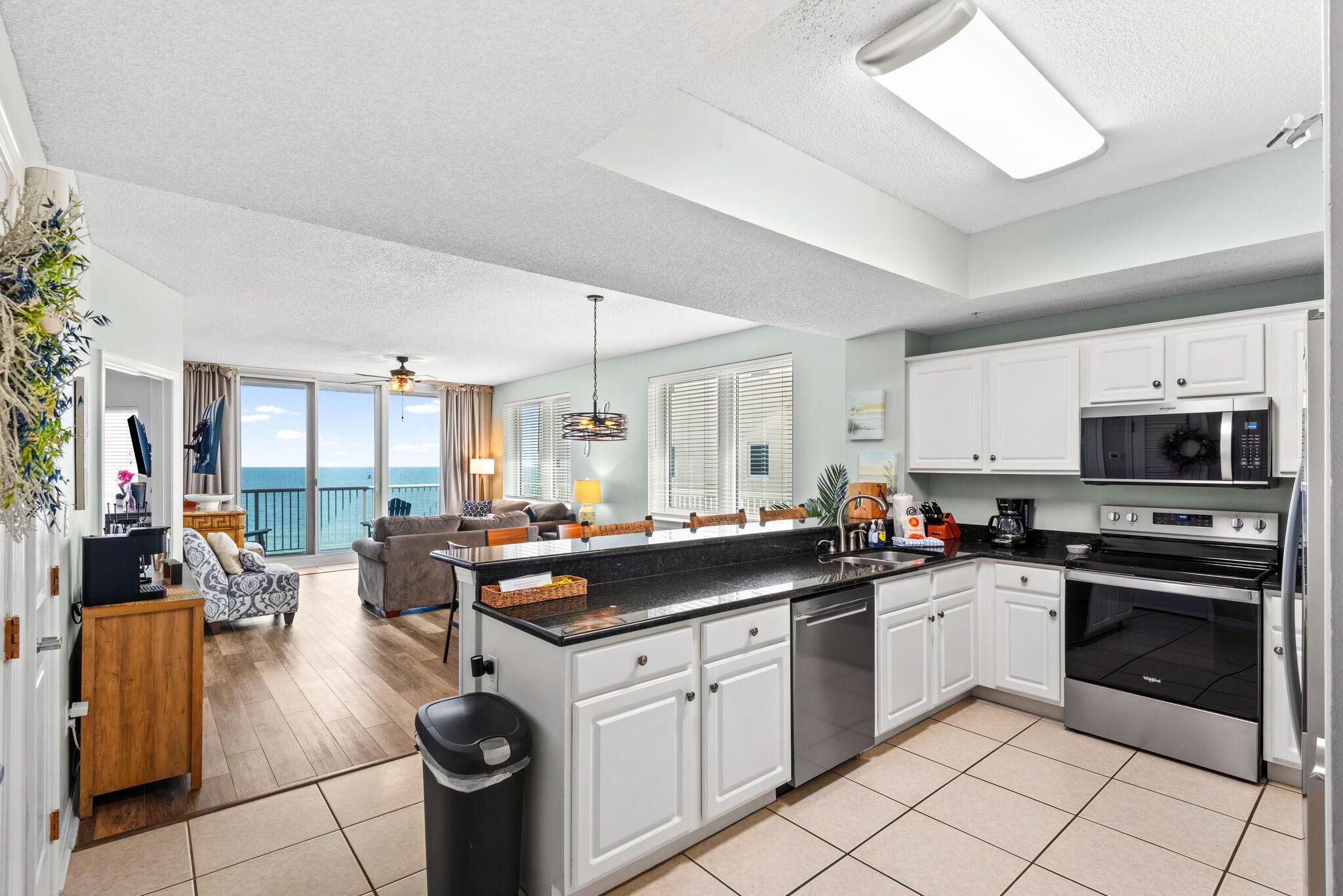 A modern kitchen with white cabinets, a black countertop, and stainless steel appliances.