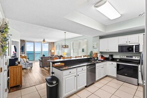 A modern kitchen with white cabinets, a black countertop, and stainless steel appliances. - Summerwind West 804 (Navarre)